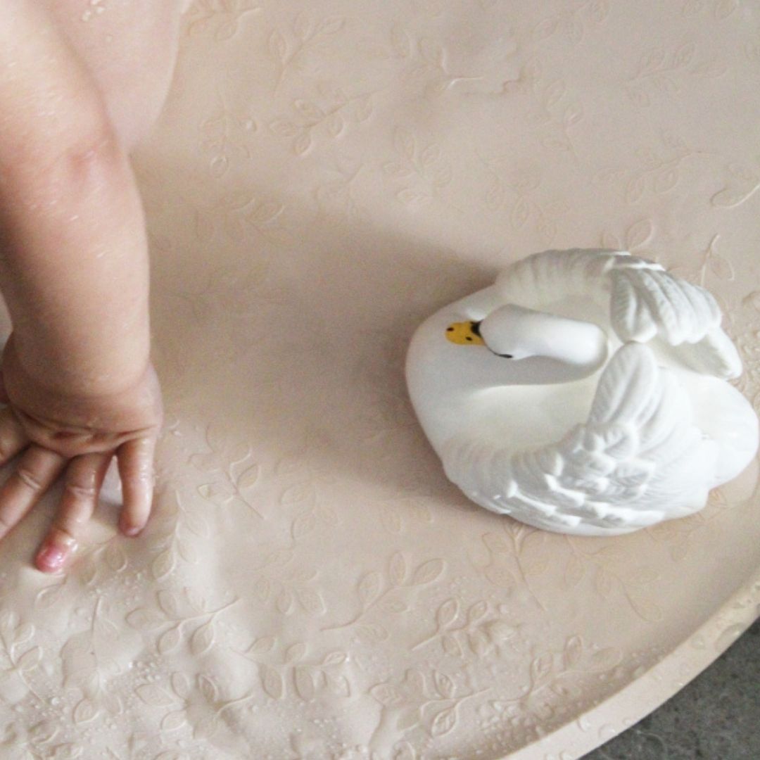 Badedyr i naturgummi formet som svane står på rund bademåtte i badet, lavet Natruba, fås hos Nordic Simply