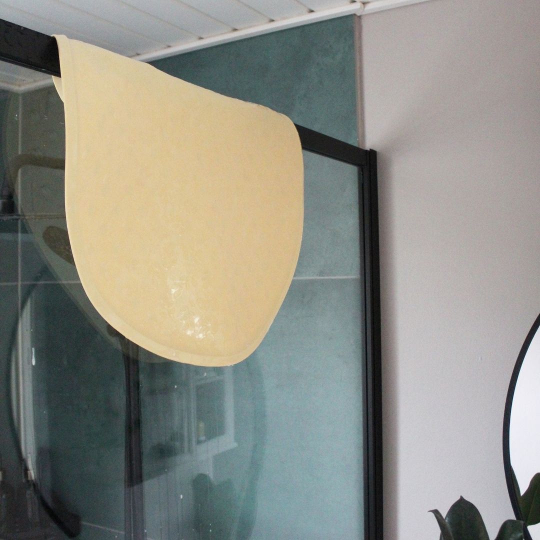 Rund gul bademåtte lavet i naturgummi fra Natruba hænger til tørre i bruseniche, fås hos Nordic Simply