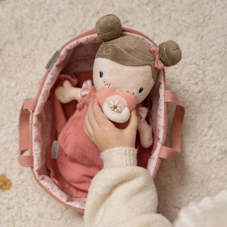 Hånd holder blød dukke Rosa i en lyserød lift, perfekt til leg for børn fra 1 år.