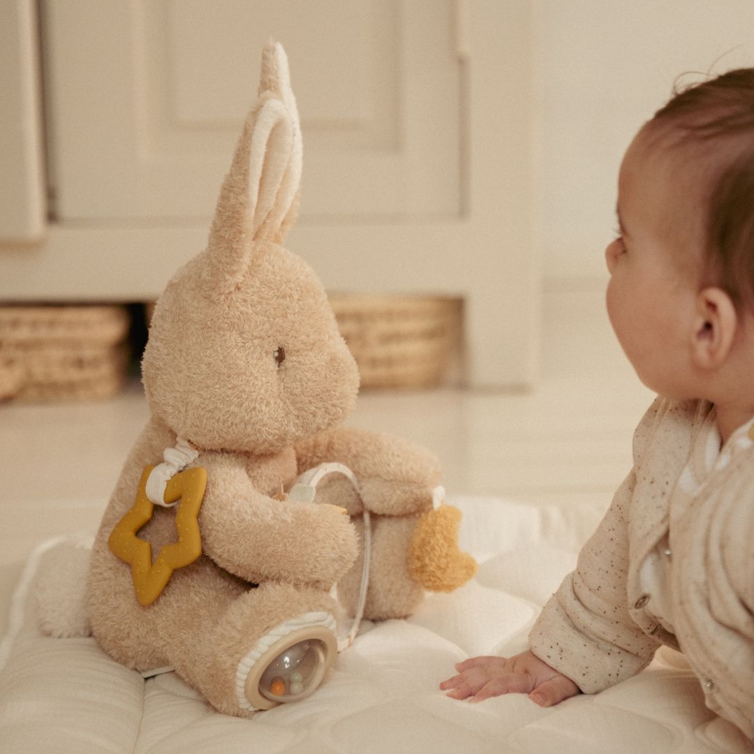 Baby i lyst værelse ser på beige kanin aktivitetsbamse fra Little Dutch, fås hos Nordic Simply