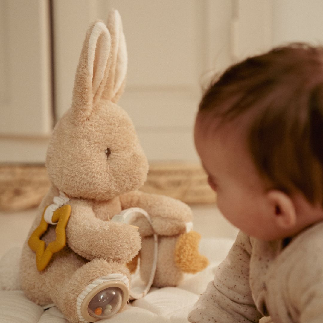 Baby i lyst værelse ser på beige kanin aktivitetsbamse fra Little Dutch, fås hos Nordic Simply