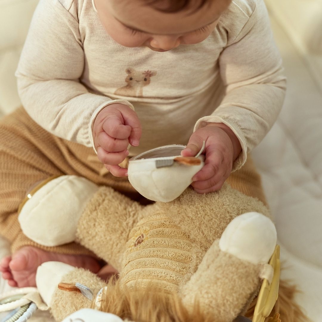 Baby undersøger spejl på løve aktivitetsbamse. En sød bamse med masser for baby at udforske fra nyfødt og op. Little Dutch.