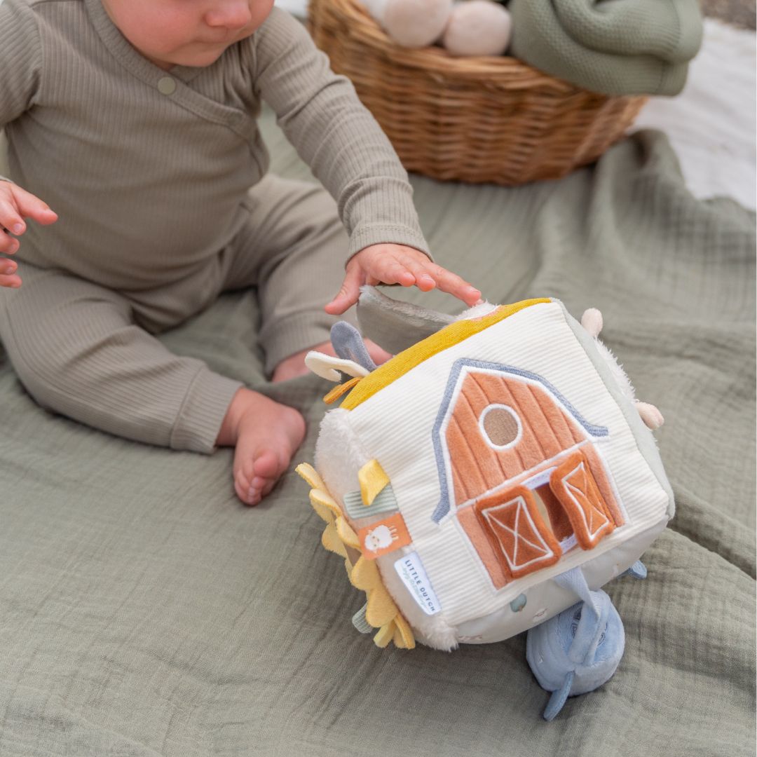 Baby sidder på grønt tæppe vog leger med blød aktivitetsterning med bondegård, fra Little Dutch fås hos Nordic Simply