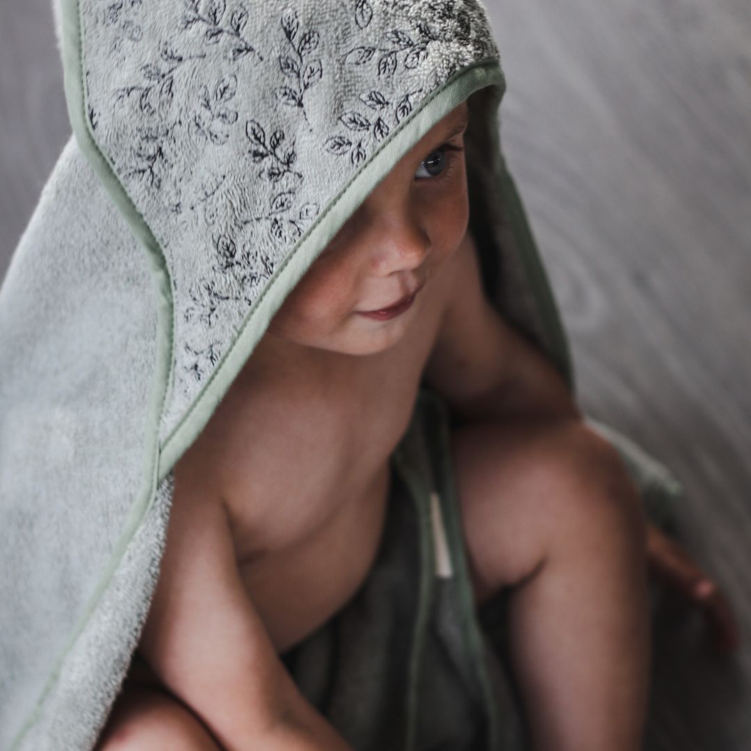 Baby i grønt badehåndklæde med hætte i 100% økologisk frotté fra Natruba fås hos Nordic Simply