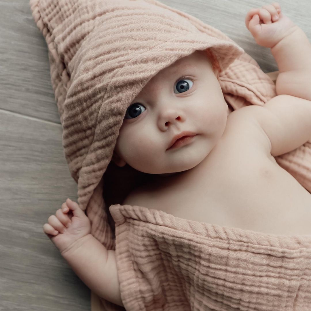 Baby i badehåndklæde med hætte i 100% økologisk rosa bomuld muslin fra Natruba fås hos Nordic Simply