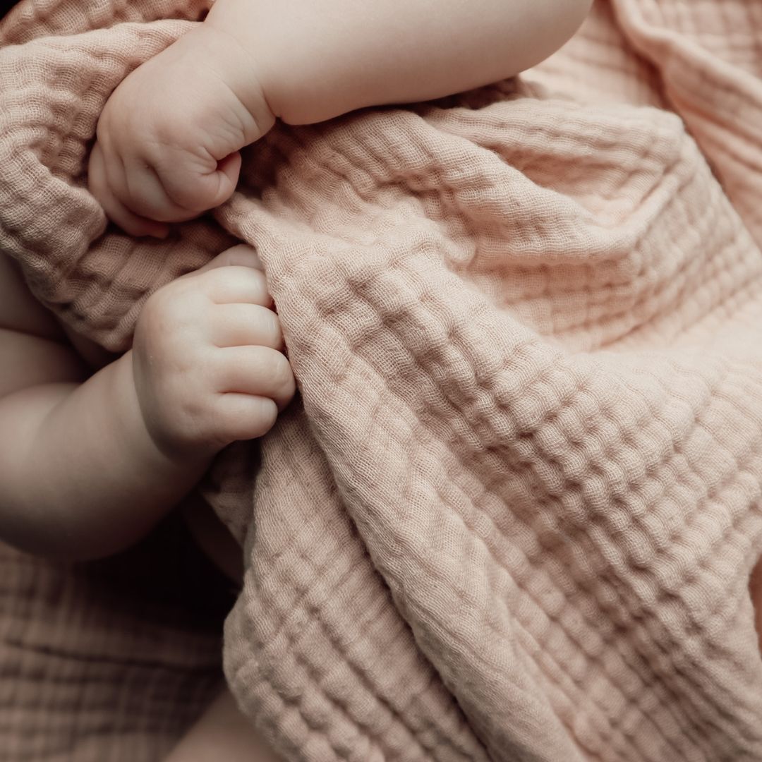 baby-hænder holder i badehåndklæde med hætte i 100% økologisk rosa bomuld muslin fra Natruba fås hos Nordic Simply
