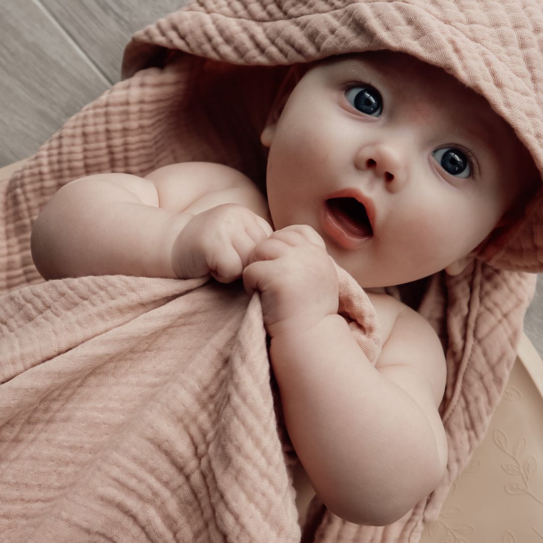 Baby svøbt i badehåndklæde i rosa med hætte i 100% økologisk rosa bomuld muslin fra Natruba, fås hos Nordic Simply