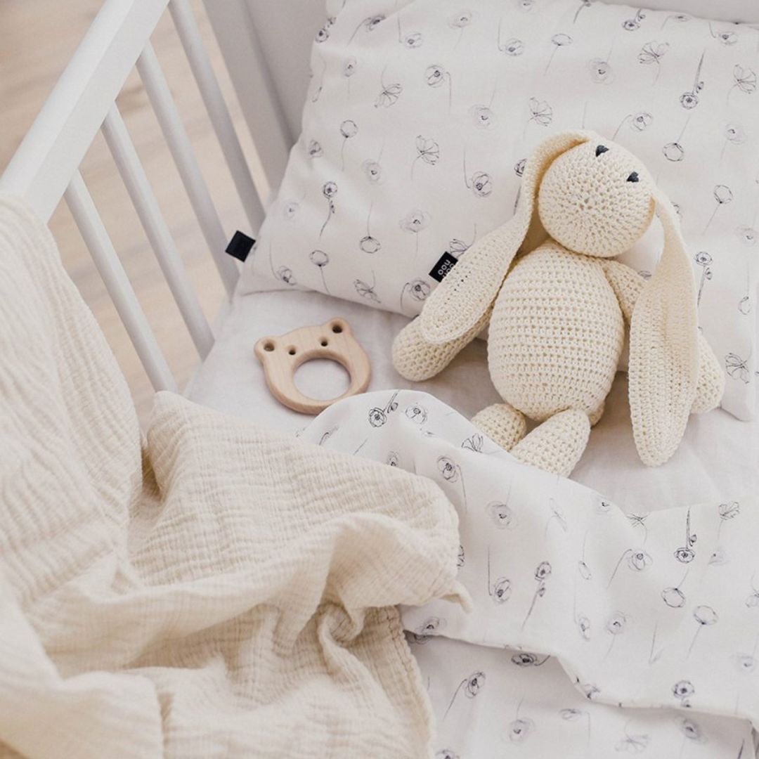 Hvidt babytæppe i tyndt bomulds muslin fra Ooh Noo , ses i babyseng, fås hos Nordic Simply