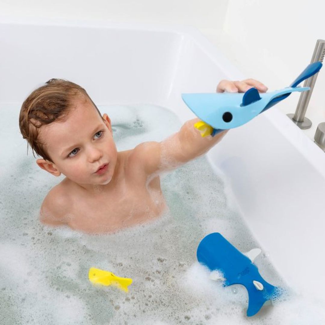 Dreng i bad med blå badehvaler af skum, badelegetøj til børn fra 3 år og op, fra Quut fås hos Nordic Simply