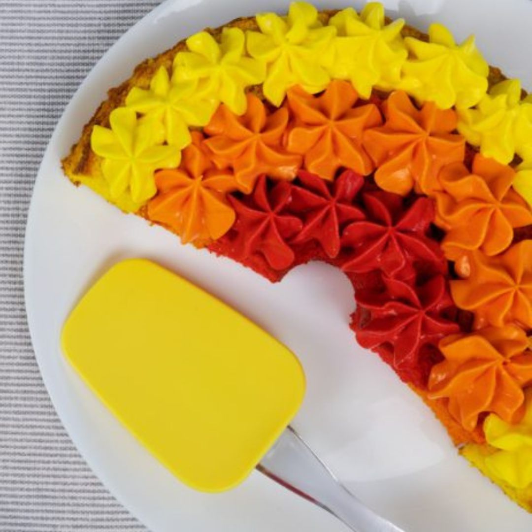 Regnbuekage i tre farver rød, orange og gul bagt i grøn regnbue bageform i silikone fra Dëna fås hos Nordic Simply