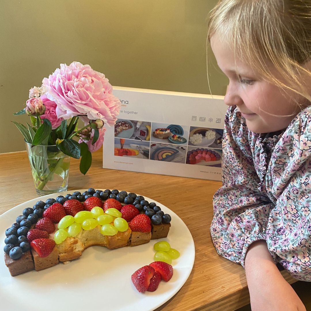 Pige ved regnbuekage med bær, bagt med med rosa regnbue bageform fra Dëna hos Nordic Simply