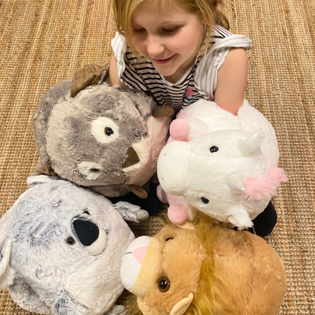 Pige med fire bamser-og håndvarmer i én fra Cozytime, forrest til højre ses stor løve bamse i størrelse XL, fås hos Nordic Simply.