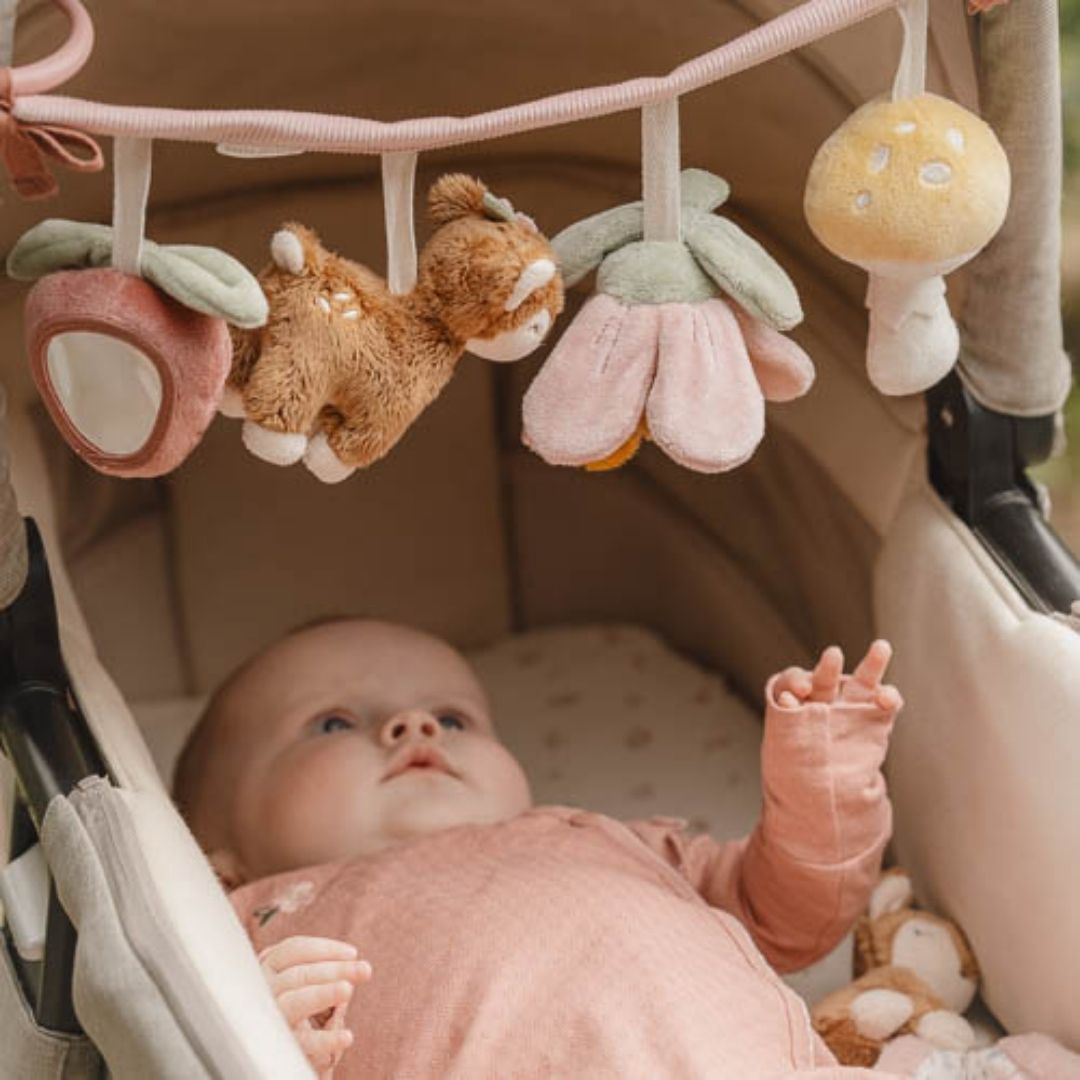 Baby i barnevogn, ser på barnevognskæde i rosa med rådyr og søde dyr fra skoven.