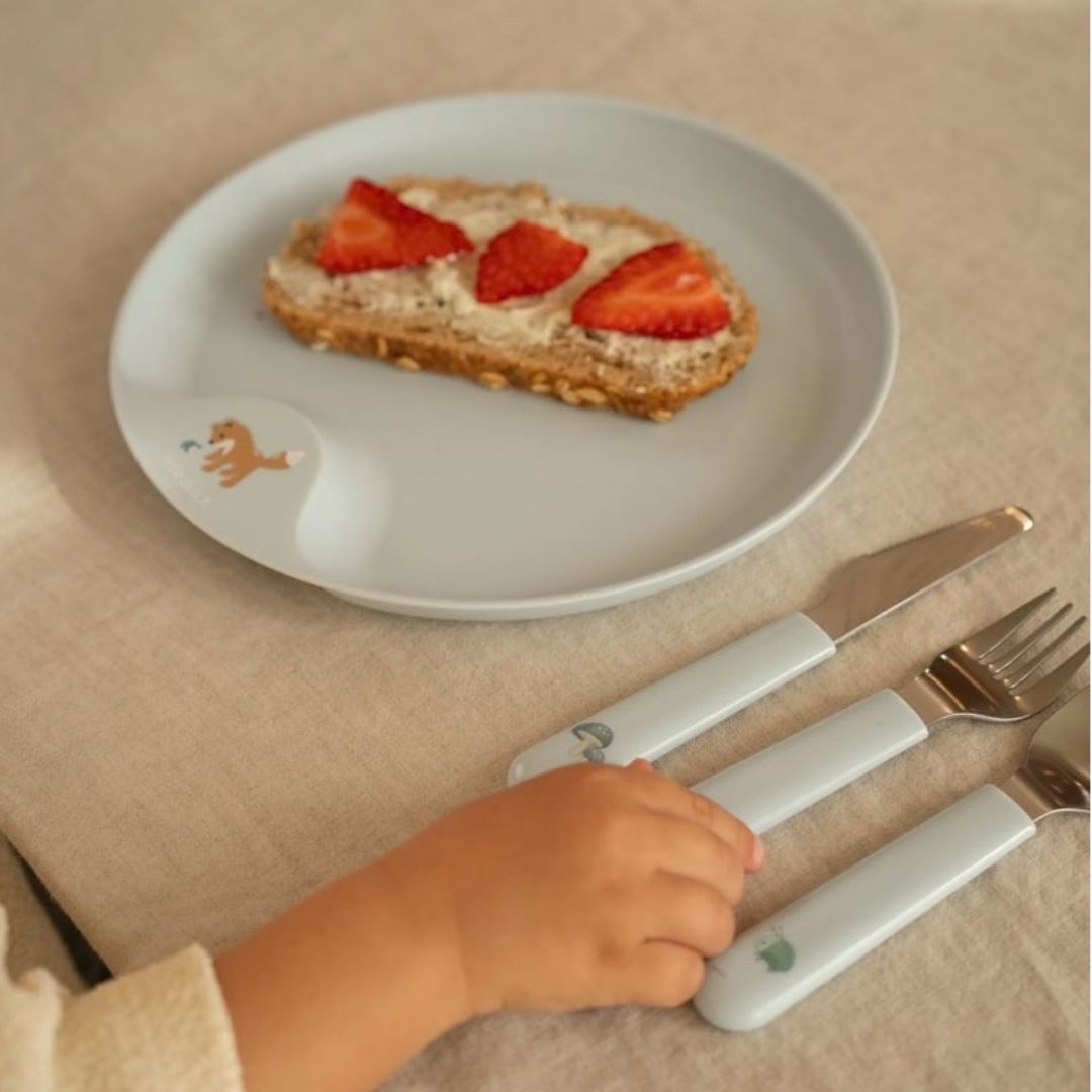 blå bestiksæt i rustfrit stål med godt greb til børn ligger ved tallerken fra samme spiseserie fra Mepal x Little Dutch