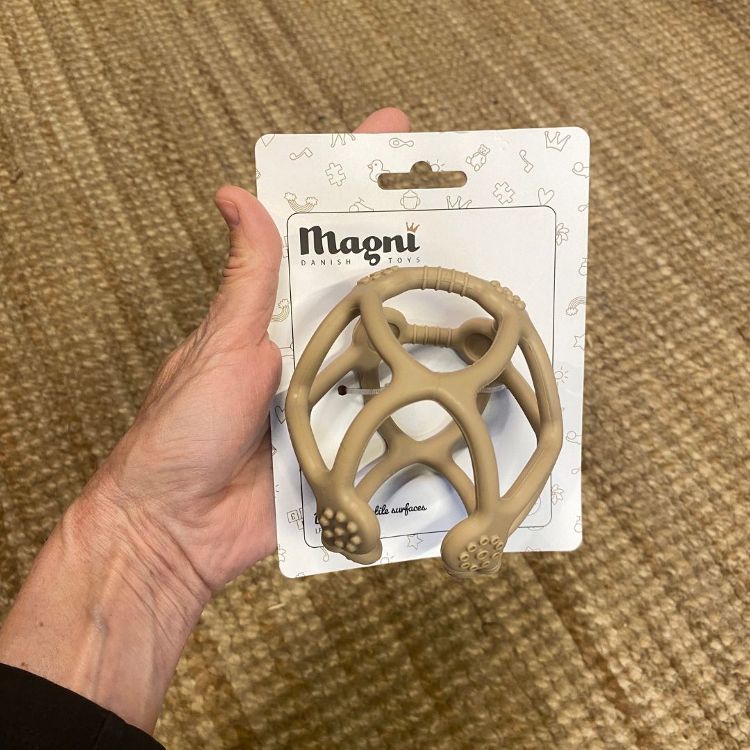 Hånd holder beige bidebold og sansebold fra Magni hos Nordic Simply