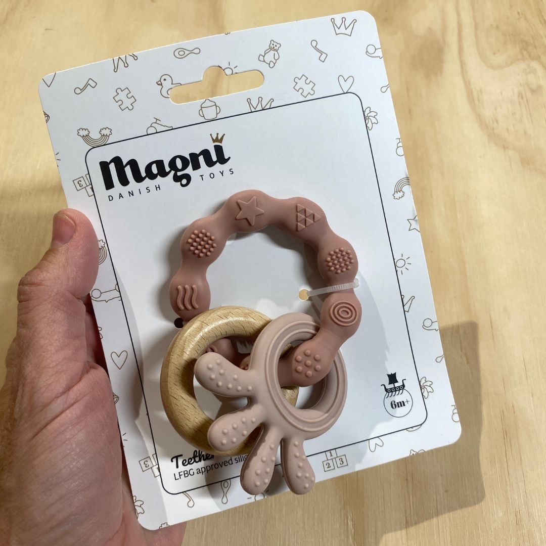 Hånd holder rosa biderangle i silikone med træring fra Magni hos Nordic Simply