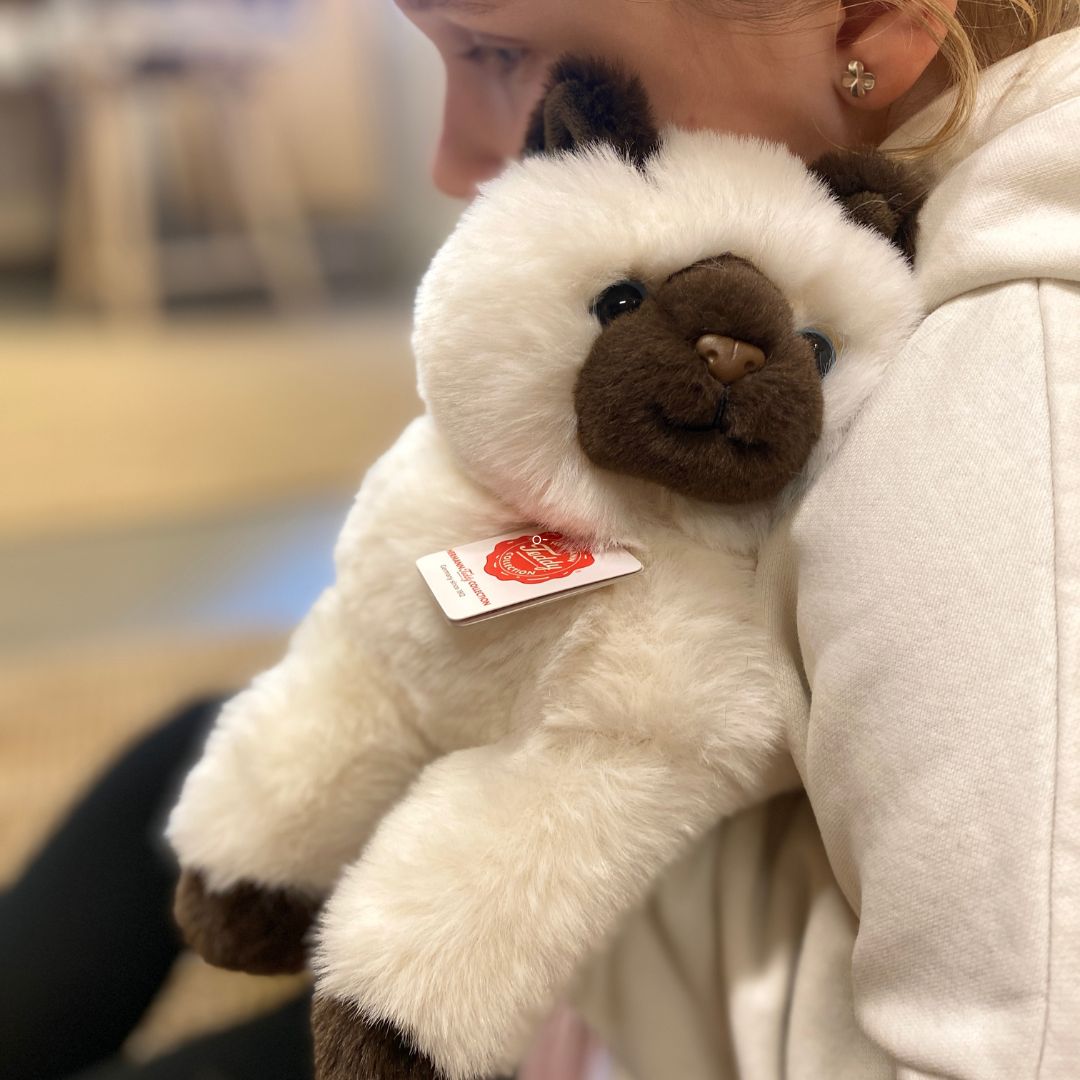 barn krammer hvid og sort Birma kattebamse med store blå øjne, fra Teddy Hermann, hos Nordic Simply