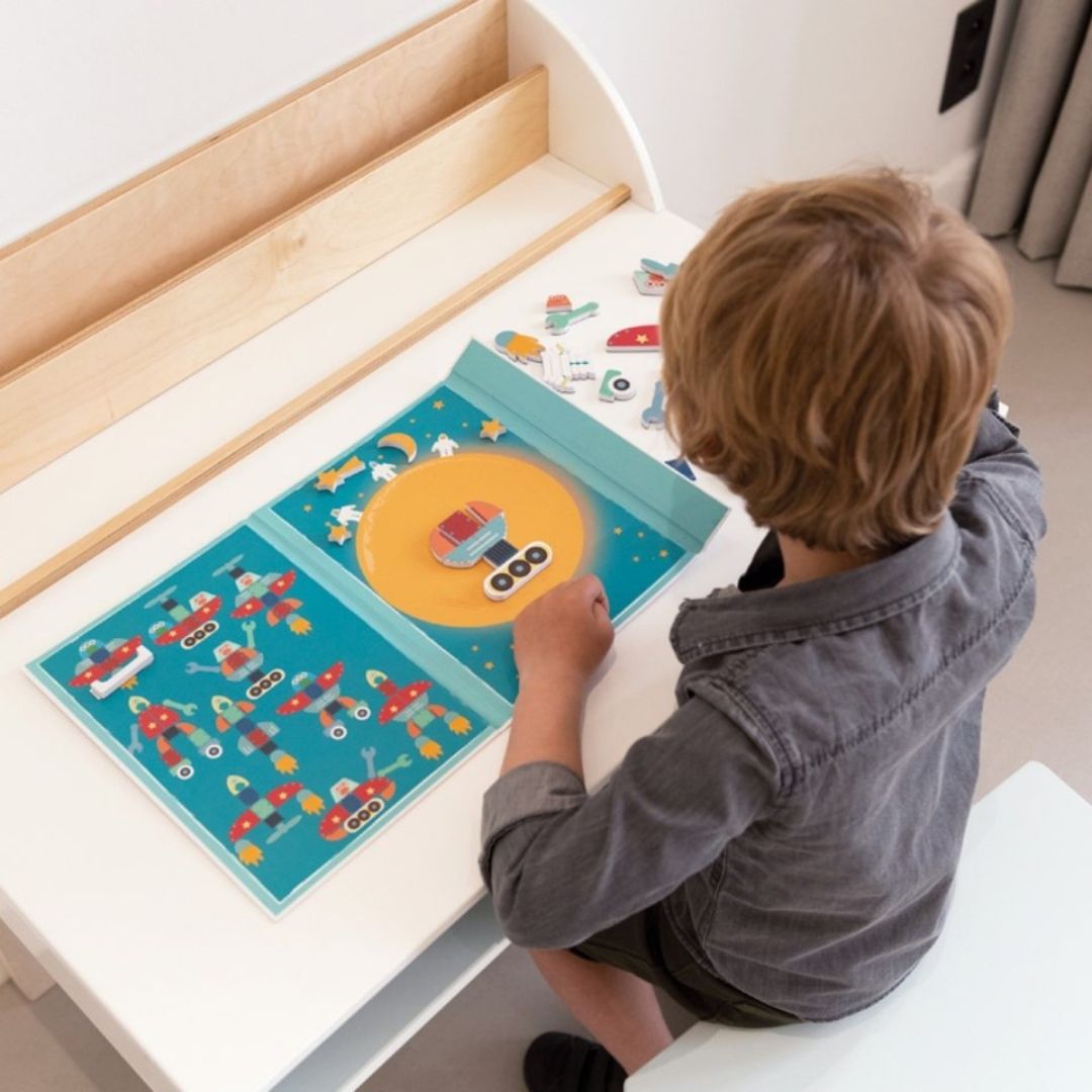 Barn ved bord med bog med magneter og figurer fra rummet fra Scratch, god til fordybelse, finmotorik og koncentration, fås hos Nordic Simply
