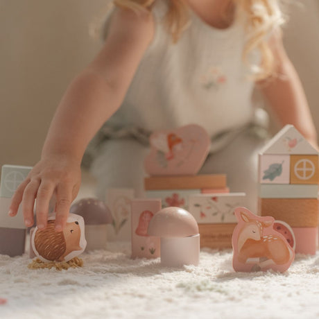 Barn leger med 50 rosa træklodser dekoreret med feer og dyr fra Little Dutch.