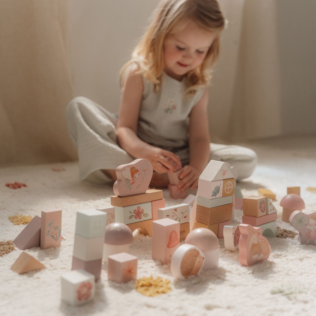 Barn leger med rosa byggeklodser fra Little Dutch, dekoreret med feer og dyr, i hyggelig stue.