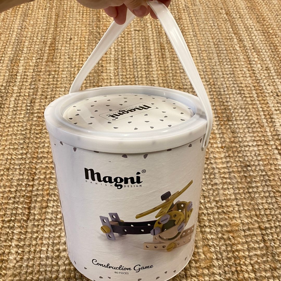 Hånd holder håndtag på spand med byggesæt i træ til børn med 80 dele fra Magni fås hos Nordic Simply