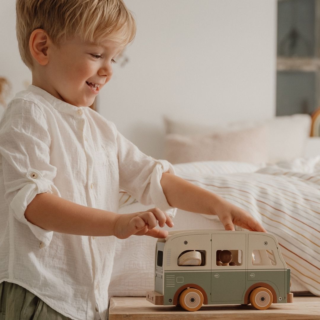Dreng skubber retrobus i træ i grøn og hvid, fra Little Dutch hen over bord, fås hos Nordic Simply