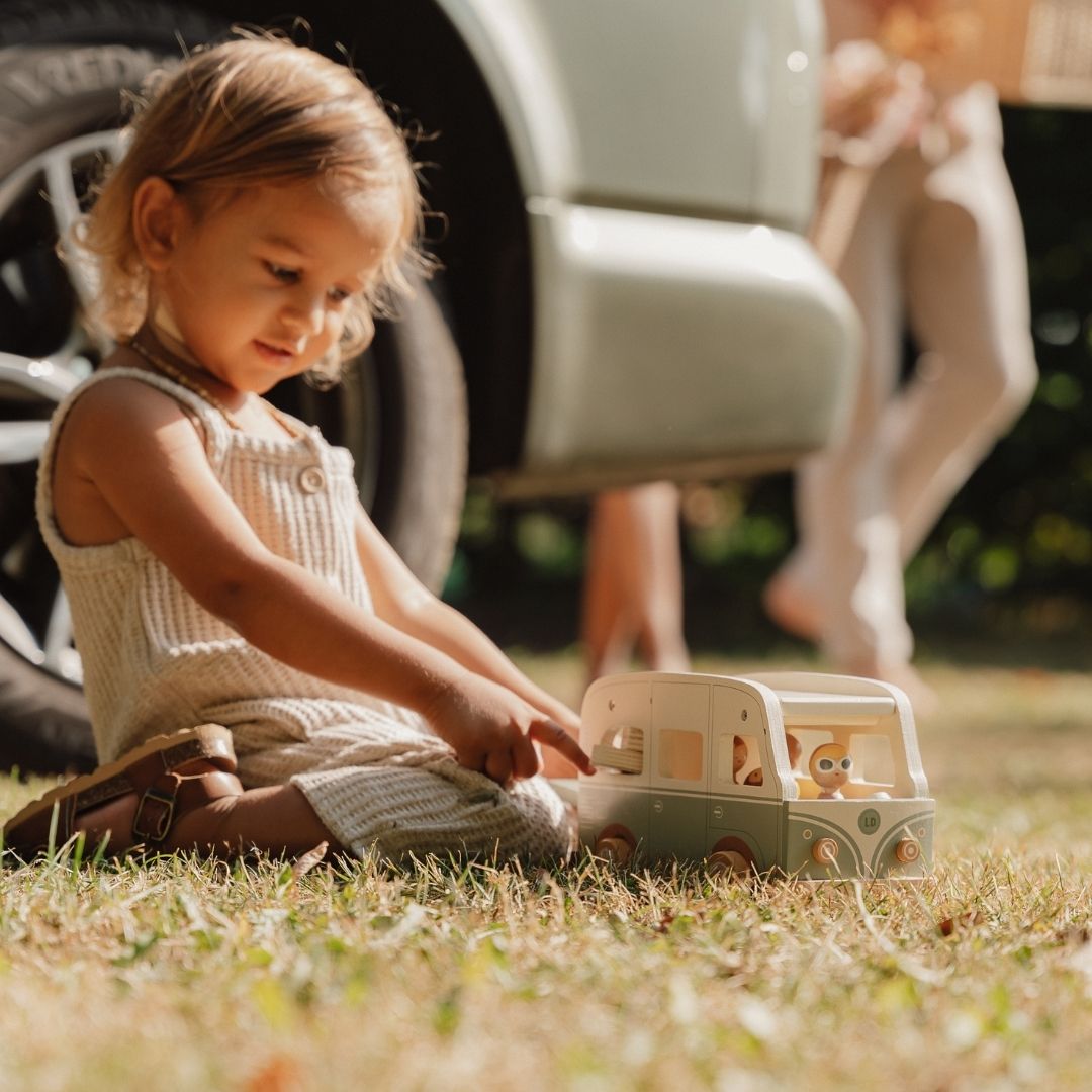 Barn leger på græs med retrobus i træ i grøn og hvid fra Little Dutch fås hos Nordic Simply