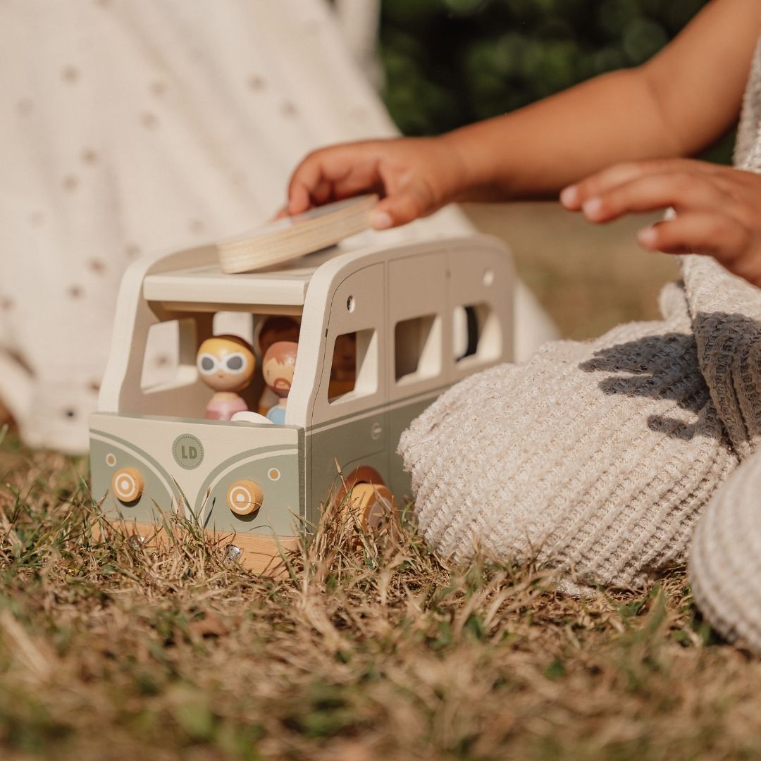 Barn leger på græs med retrobus i træ i grøn og hvid fra Little Dutch fås hos Nordic Simply
