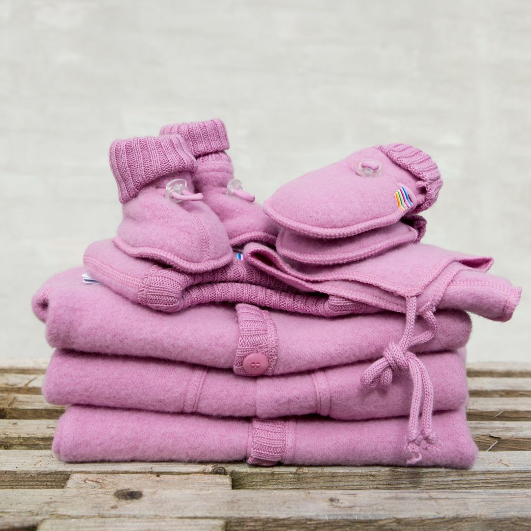 Rosa cardigan i blød merinould fra Joha, her set i stak sammen med futter og vanter i samme farve, perfekt til babys første køreture.