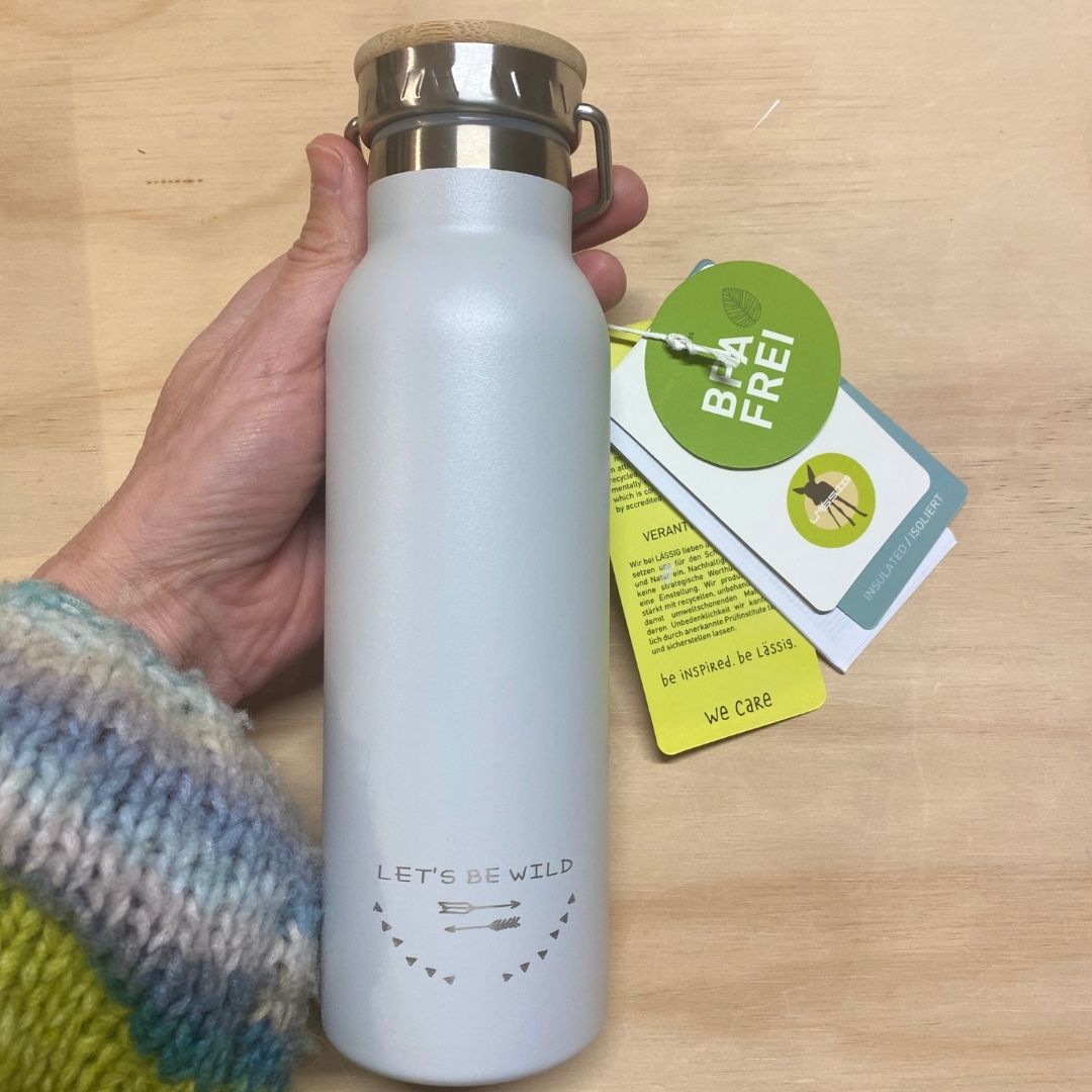 Hånd holder termoflaske i rustfrit stål i lys grå med bambuslåg, indeholder 460 ml fra Lässig fås hos Nordic Simply