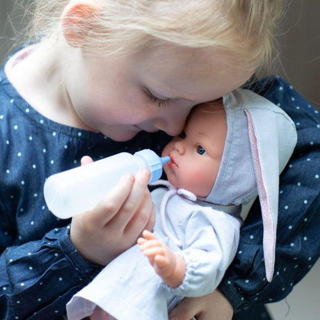 Pige giver dukke, i grå dragt med kaninører, sutteflaske. Kvalitetsdukke fra spanske Así fås hos Nordic Simply