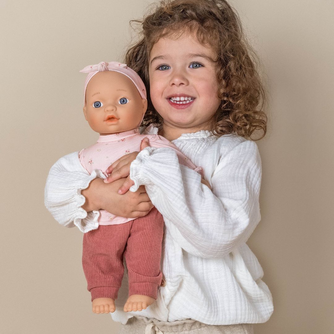 Dukke Lily med udstyr, 36 cm, trygt i armene på en glad lille pige.