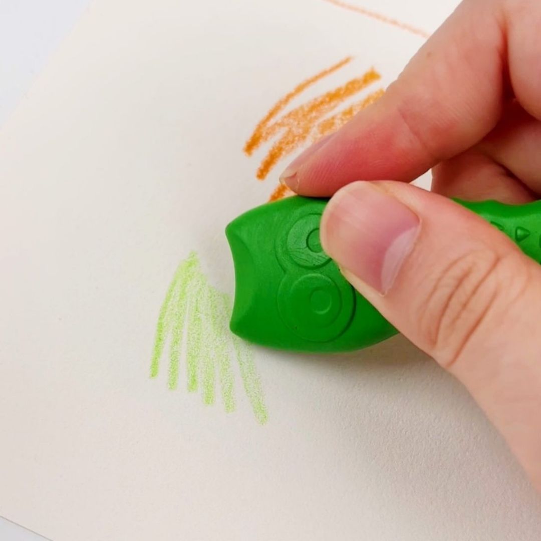 Hånd tegner med grøn ugleformet farve fra Haku Yoka med bivoks. Perfekt til kreativ leg for børn.