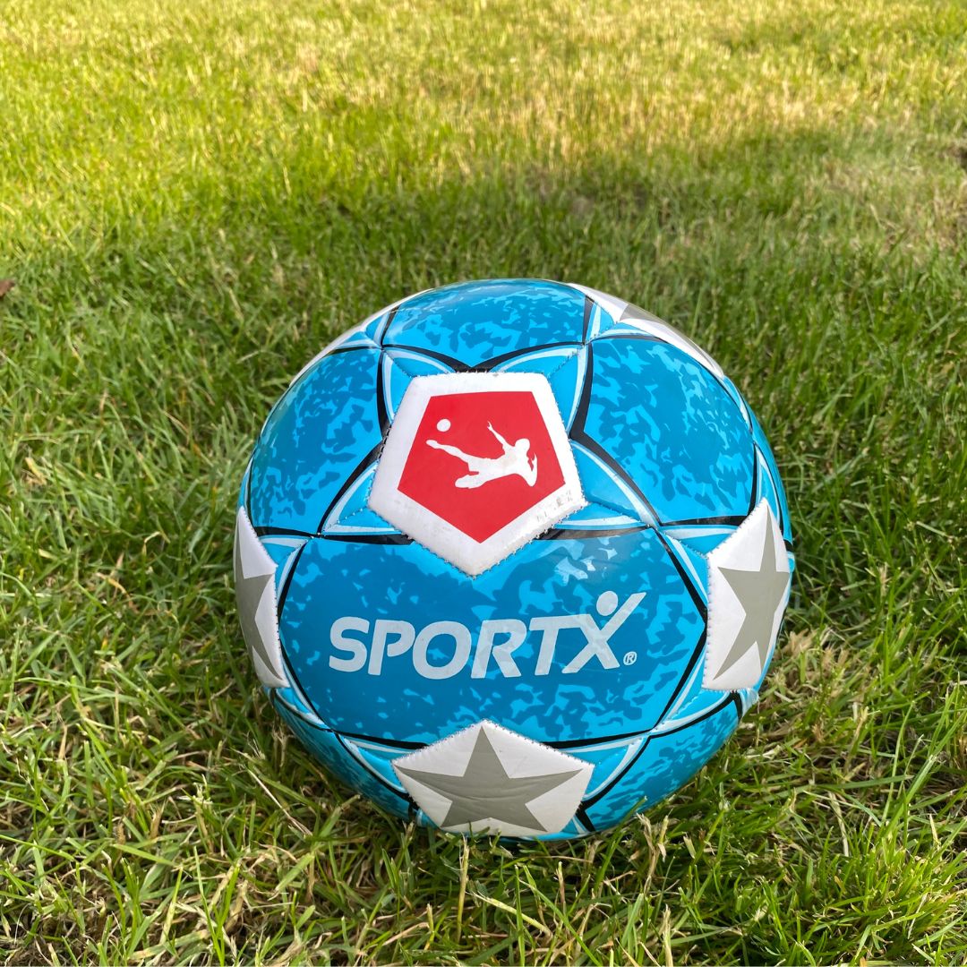 Blå fodbold med sølvstjerne ligger på græsplæne klar til leg hos Nordic Simply