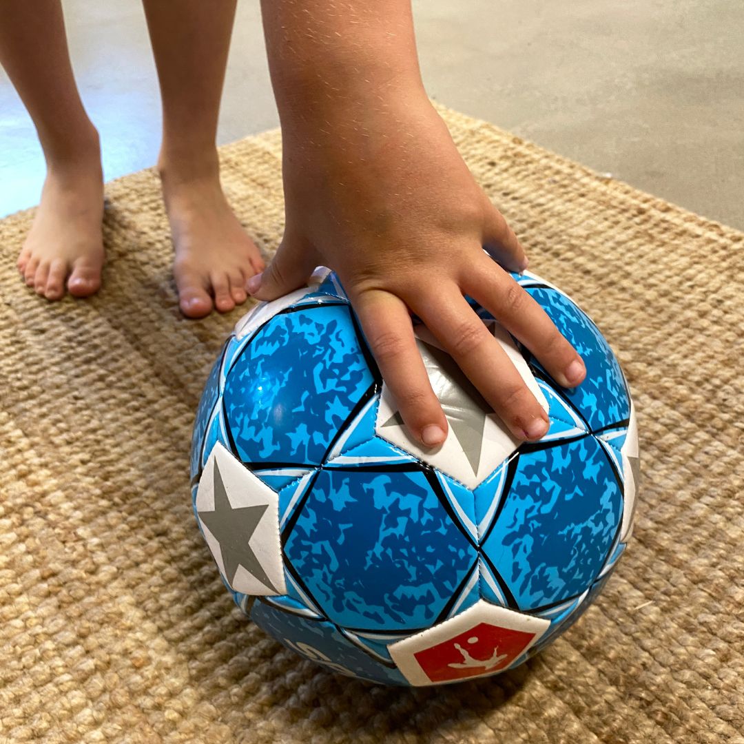 Barn samler blå fodbold med sølvstjerner op fra gulv hos Nordic Simply