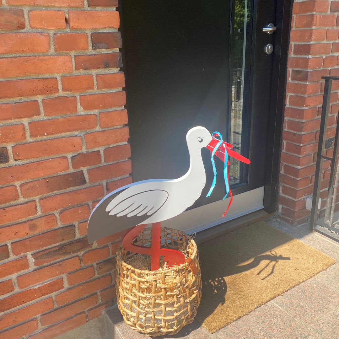 fødselsstork og barselsstork 80 cm fra Magni står foran sort hoveddør klar til at fejre en lille ny, set hos Nordic Simply