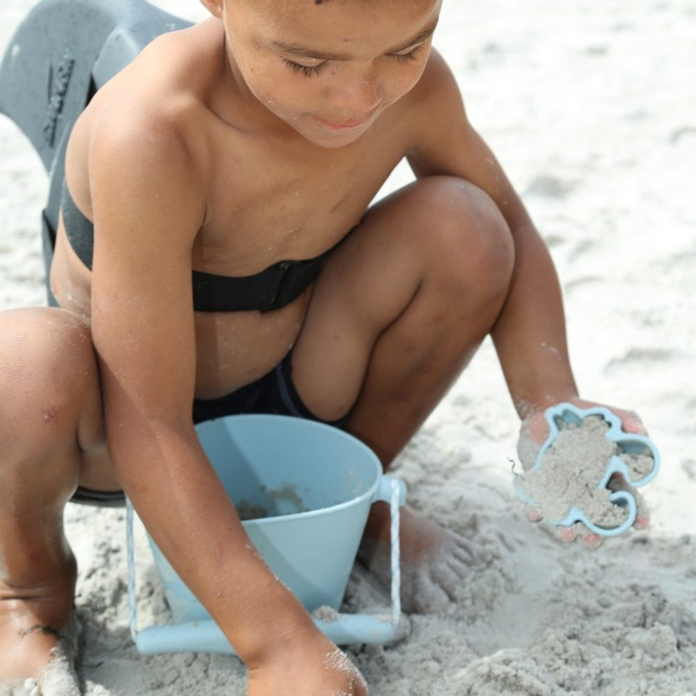 dreng leger på strand med blå sandforme i silikone, perfekt til små hænder fra 1 år og op, høj kvalitet fra Scrunch