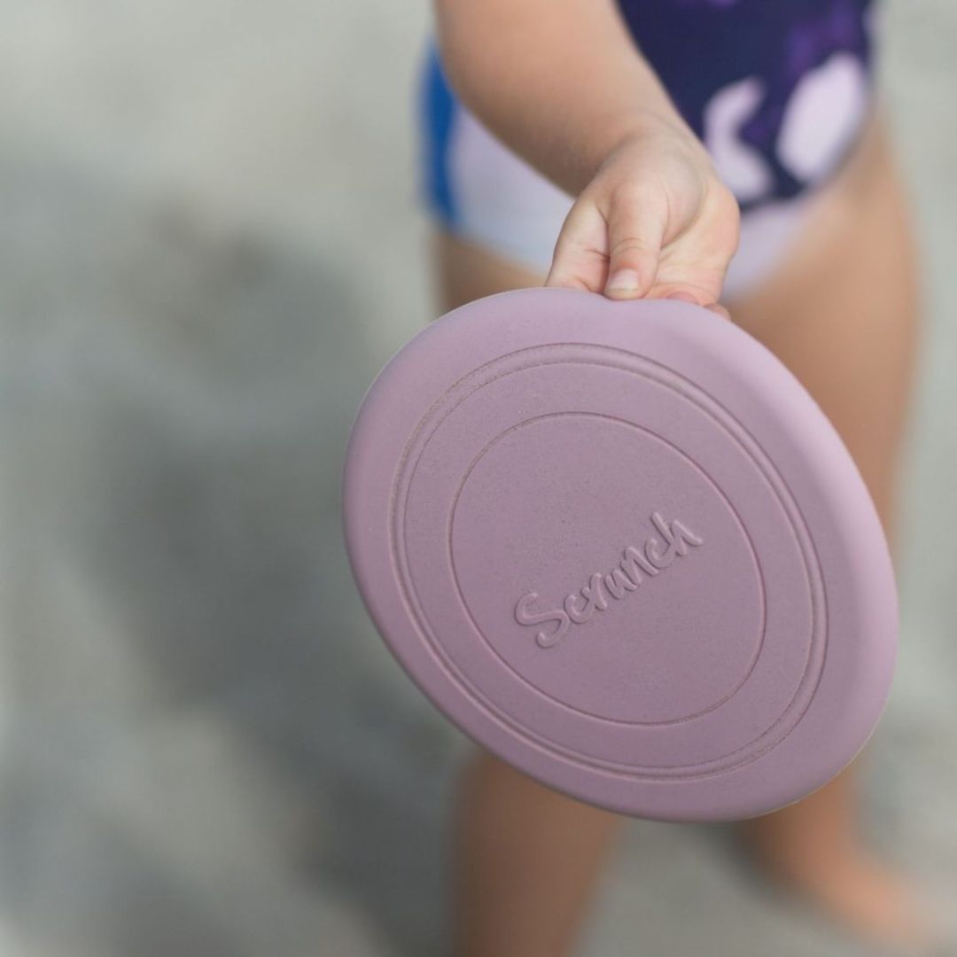 Hånd holder holder rosa frisbee i silikone fra Scrunch, en blød disc der flyver godt, og som kan foldes fås hos Nordic Simply