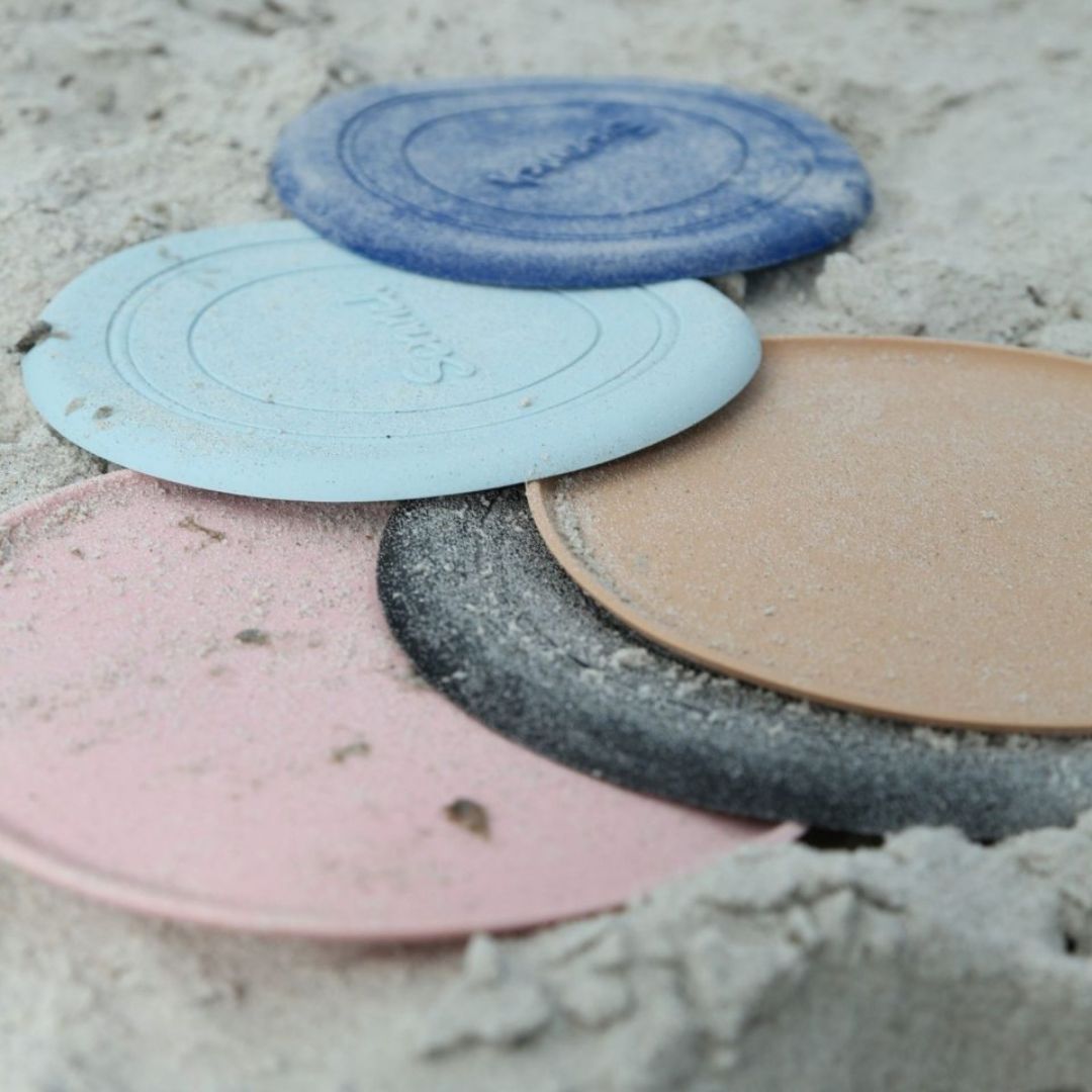 Frisbees i silikone fra Scrunch ligger i bunke på strand, brun frisbee fås hos Nordic Simply