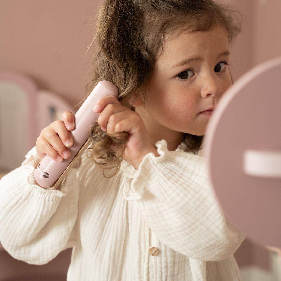 Mini frisør i aktion med frisørsæt i træ med hoftebælte ved spejl.