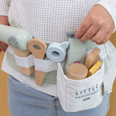 Barn med frisørsæt i træ, sidder i smart bælte som barnet har om maven, her ses hårtørrer, saks, shampoo, kam og andre dele til en lille frisørsalon, kvalitetslegetøj fra Little Dutch fås hos Nordic Simply