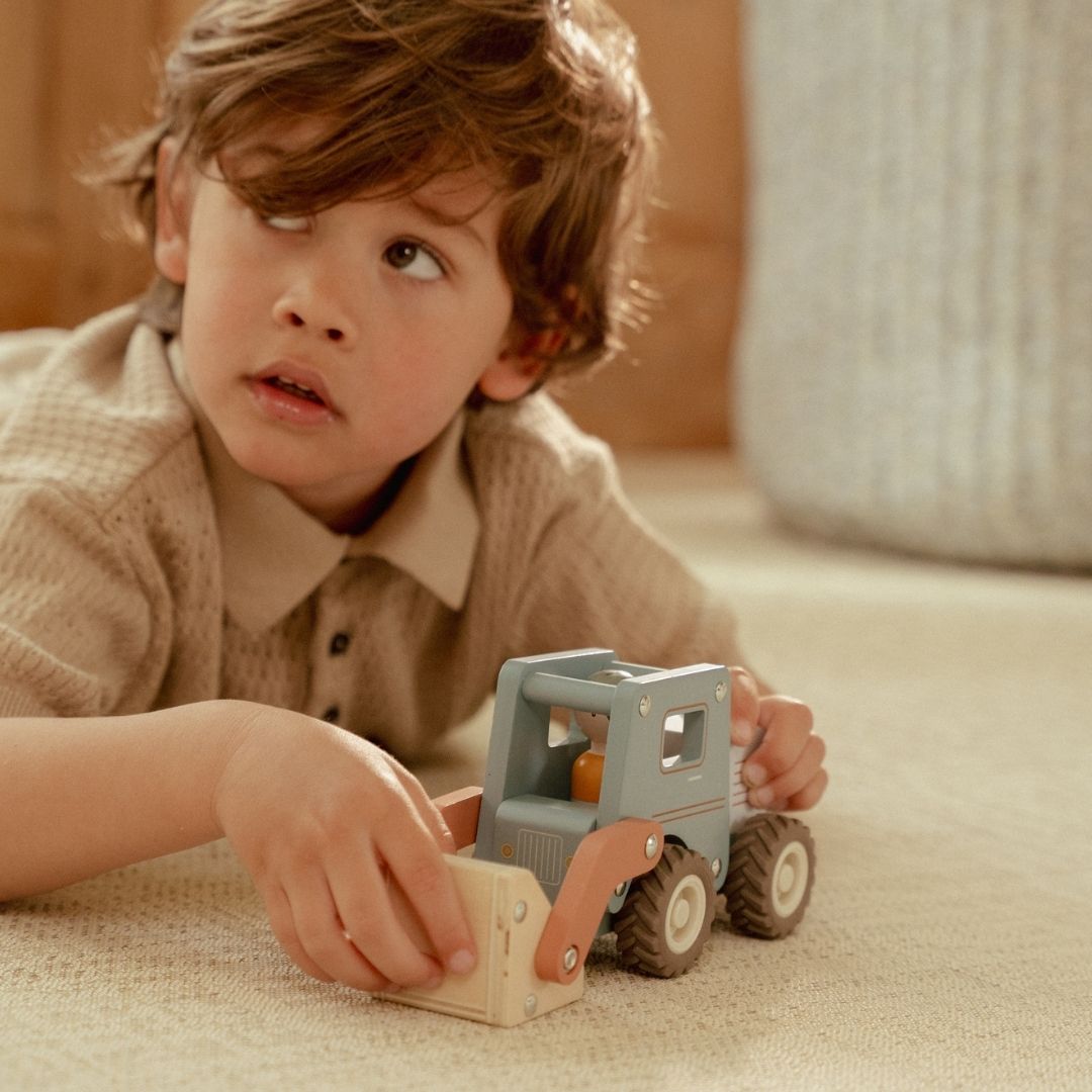 Frontlæsser med træfigur: dreng leger med blå træ frontlæsser på lyst gulvtæppe