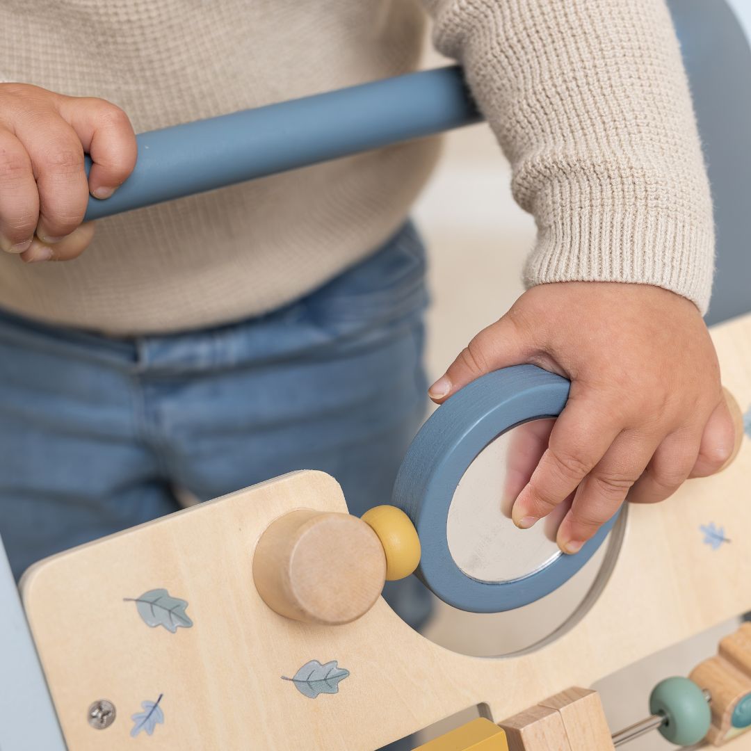 Barn drejer på rundt spejl på blå aktivitets gåvogn i træ fra Little Dutch, med 8 spændende aktiviteter at opdage og udforske.