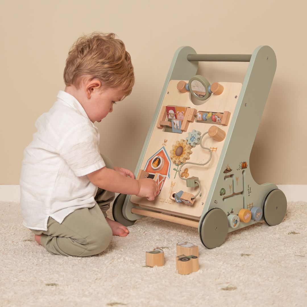 Dreng leger med grøn gåvogn i træ med 8 bondegårdsaktiviteter fra Little Dutch, i stue.