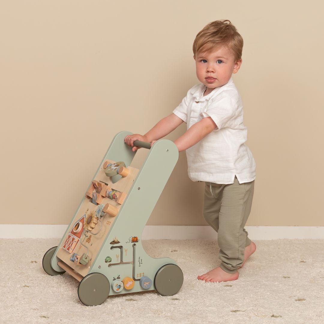 Dreng skubber grøn gåvogn i træ med 8 bondegårdsaktiviteter fra Little Dutch, designet til støtte motorisk udvikling for børn fra 1 år.