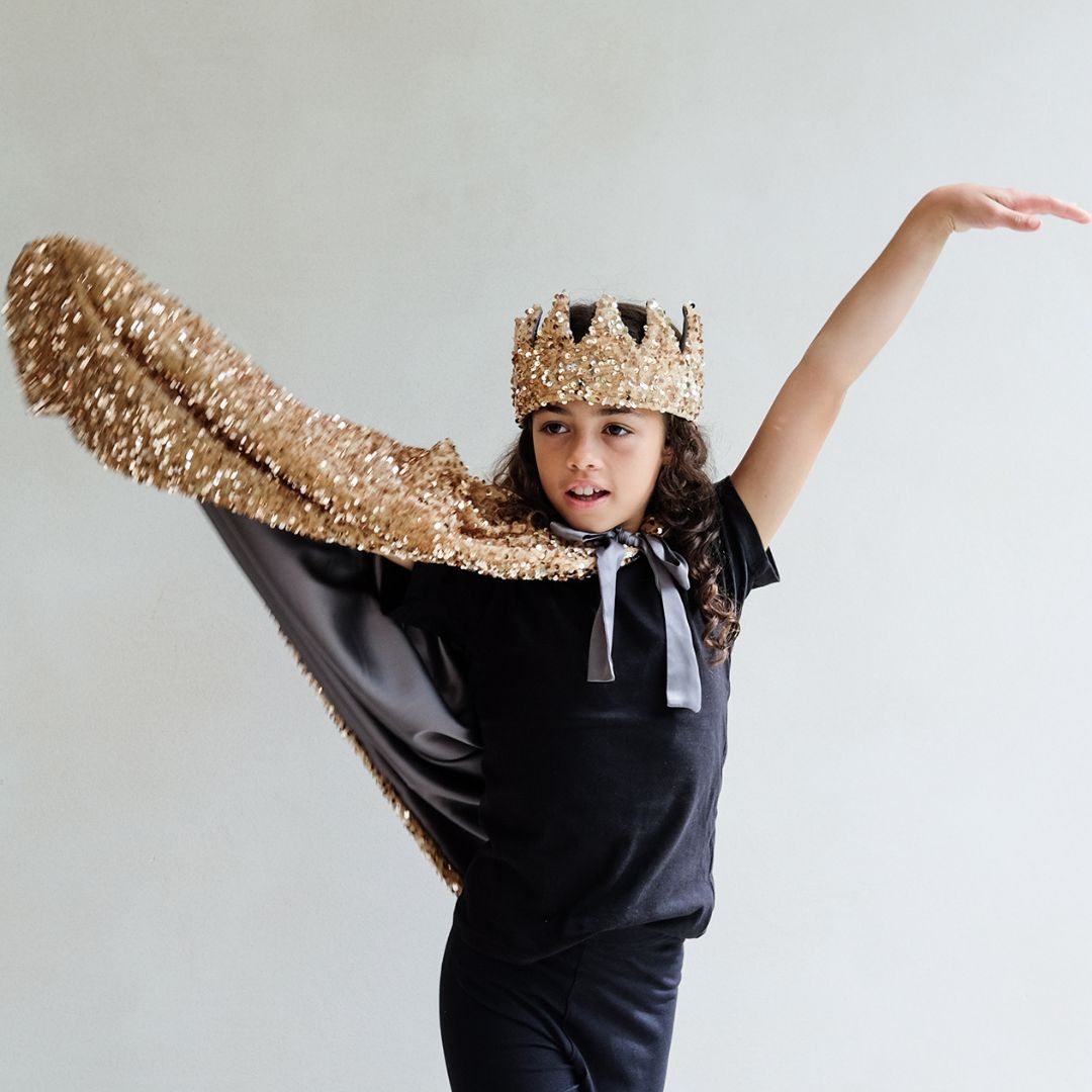 Barn i lang guldkappe med pailletter og krone, eksklusiv udklædning til magi og fantasi.