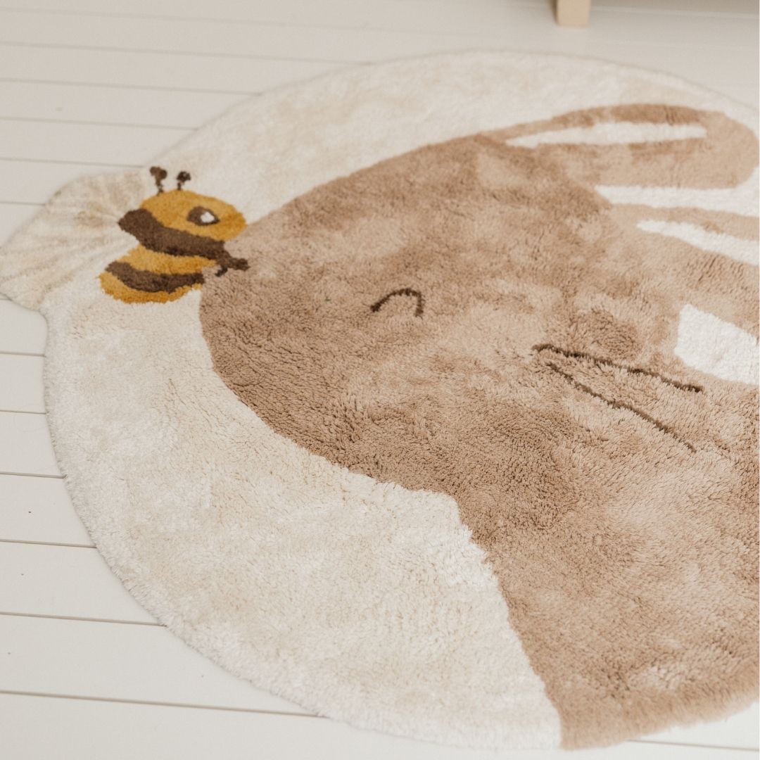 Blødt gulvtæppe med kanin, rundt beige legetæppe i økologisk bomuld med sød kanin og bi, set tæt på, smuk indretning af børneværelset