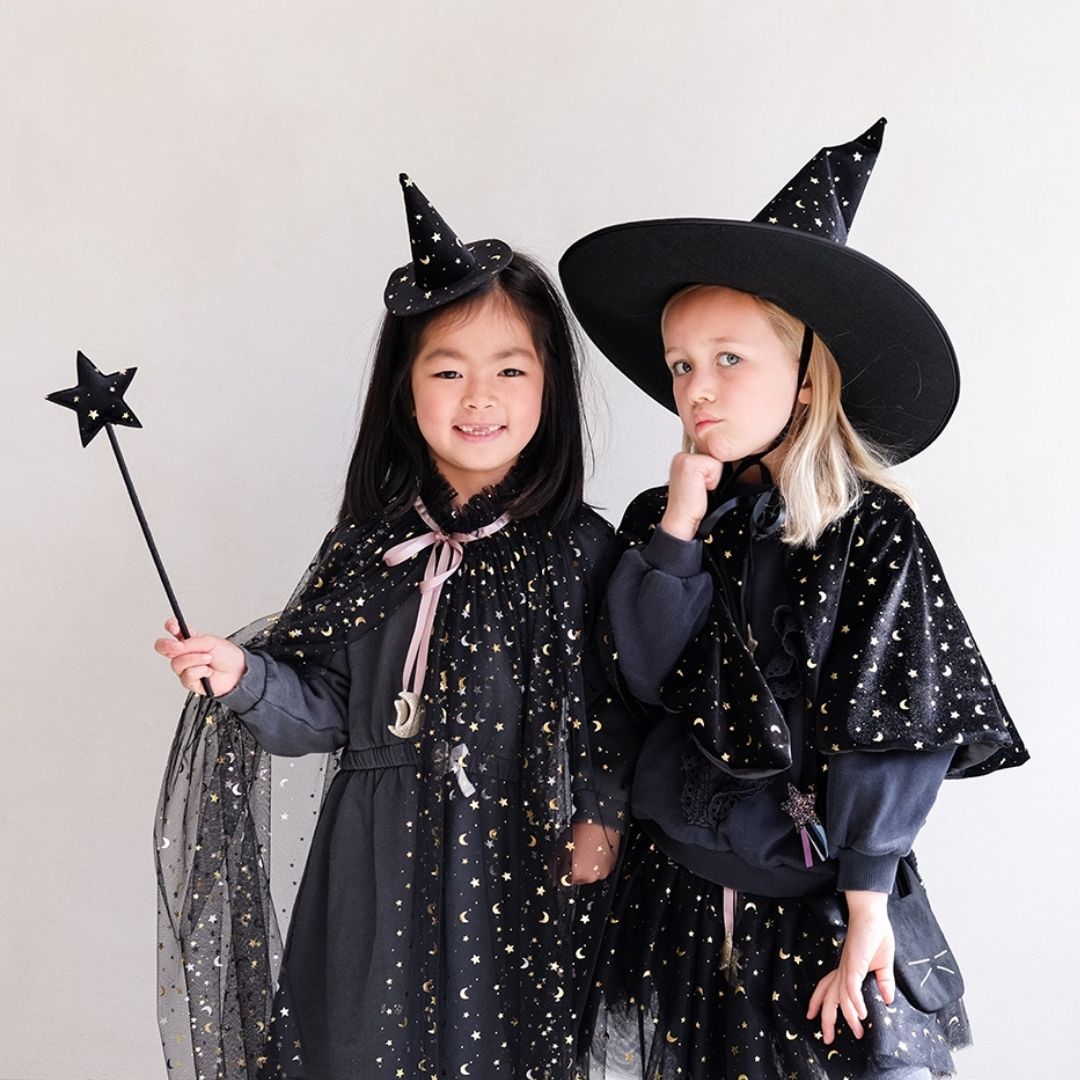 To piger i sort udklædning som hekse, en pige bærer lille heksehat på hårbøjle i sort velour med stjerner, fra Mimi & Lula fås hos Nordic Simply