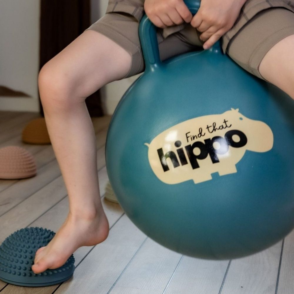 Dreng der leger på en blå hoppebold fra Find that Hippo fås hos Nordic Simply, perfekt til børn fra 2 år og op.