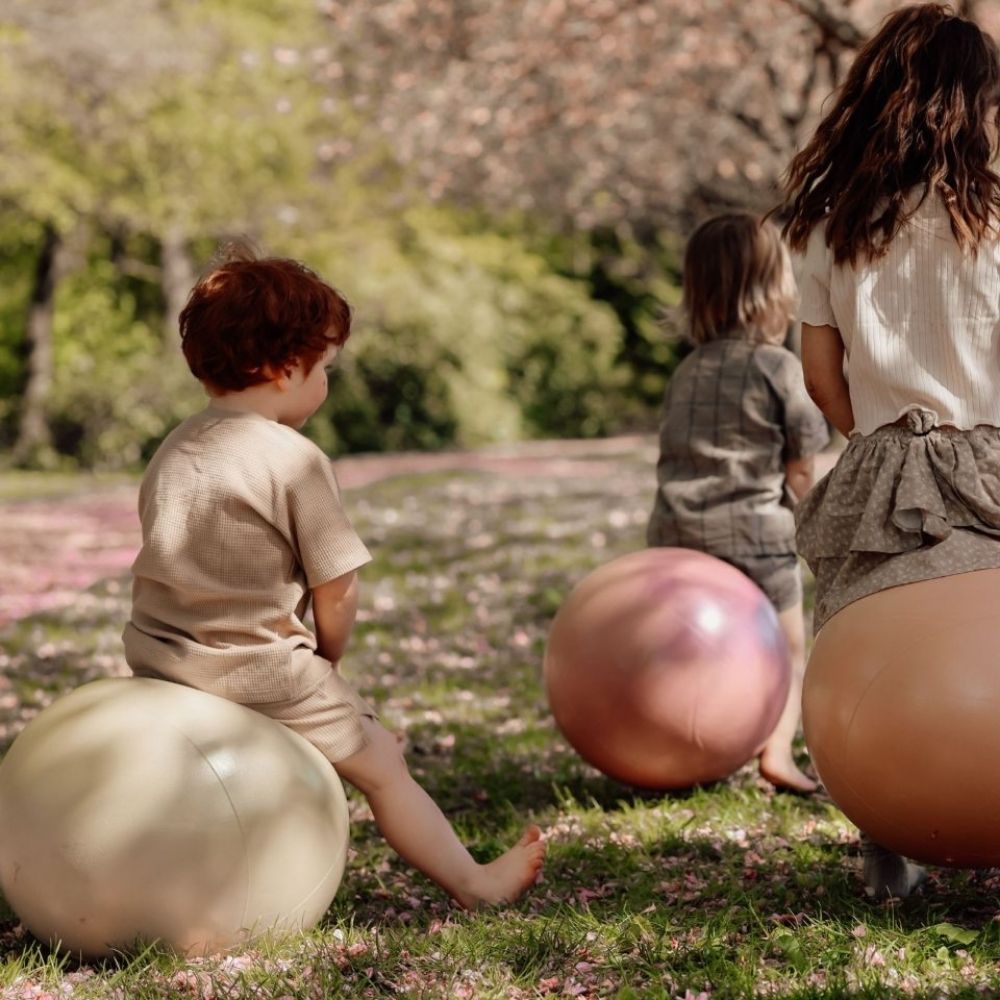 Børn leger i en park med grøn, rosa, og orange hoppebolde fra Find that Hippo til sjov, aktiv leg og motorisk træning, fås hos Nordic Simply